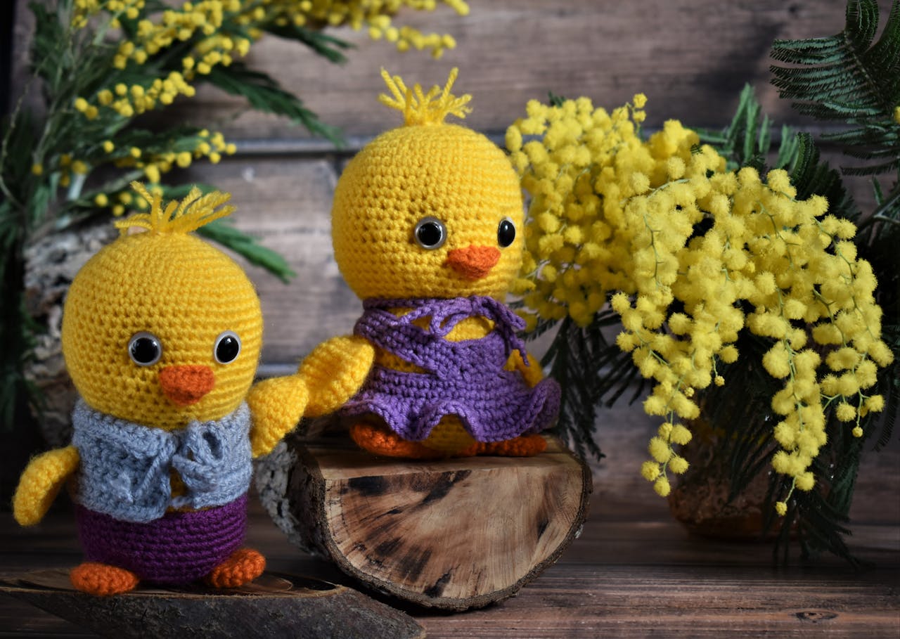 Handmade crocheted chicks with vibrant flowers, perfect for Easter decoration.