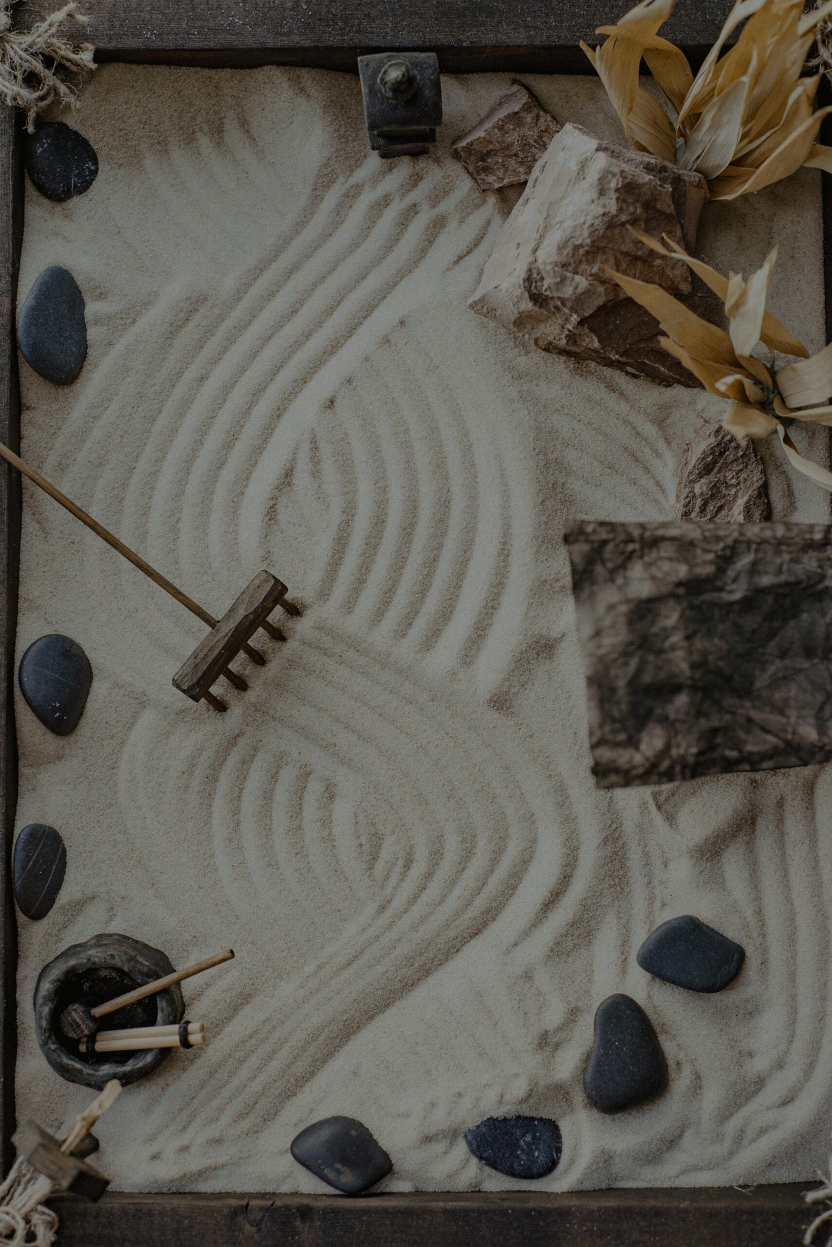 Tranquil zen garden with raked sand, stones, and dried plants creating a calming vibe.